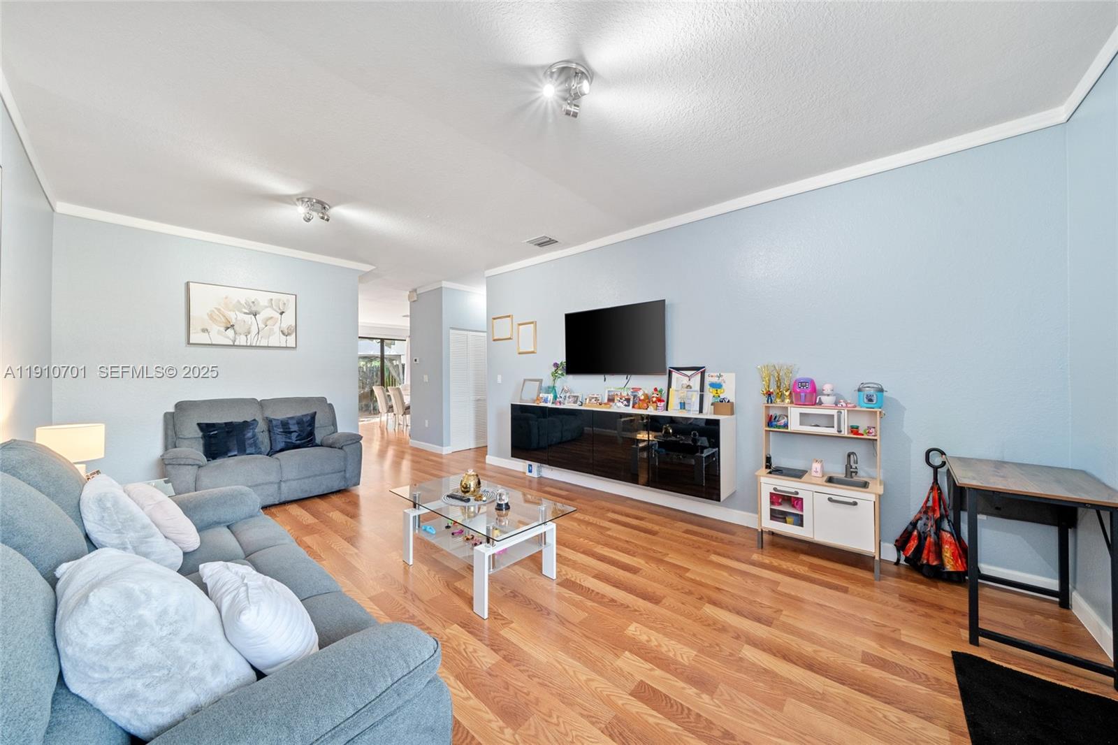 23713 Southwest 115th Avenue Homestead, FL 33032 - Photo 3 of 26 a living room with furniture a flat screen tv and wooden floor
