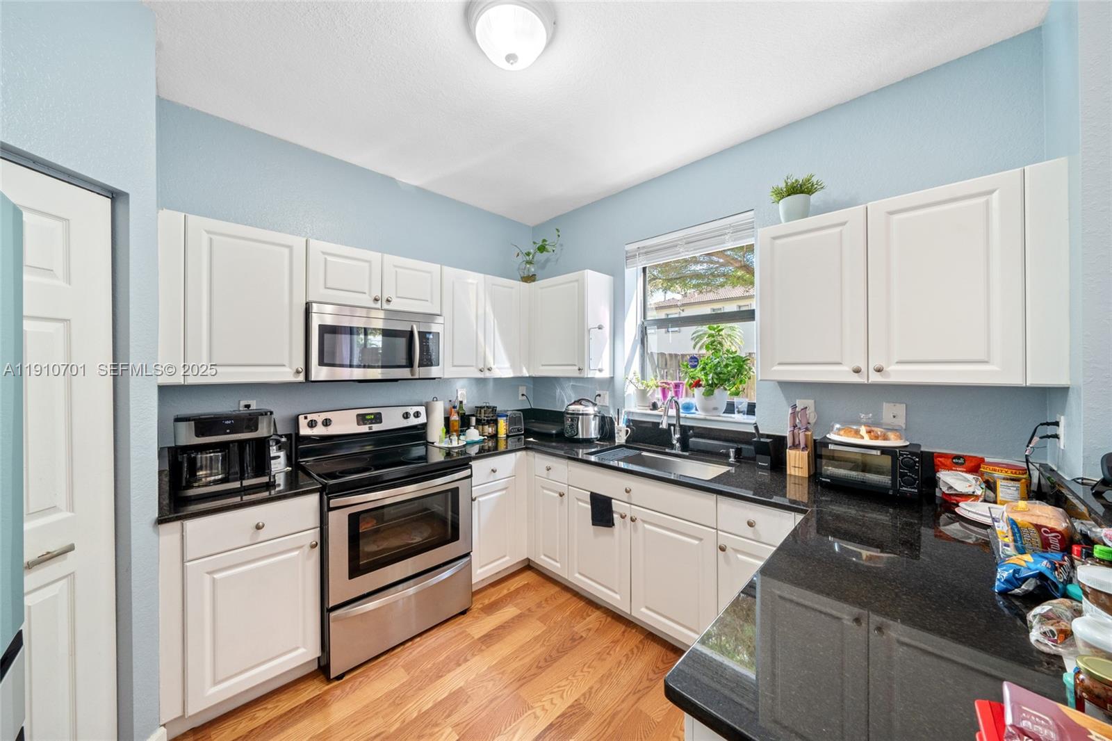 23713 Southwest 115th Avenue Homestead, FL 33032 - Photo 6 of 26 a kitchen with stainless steel appliances granite countertop white cabinets a sink a stove a refrigerator and white cabinets