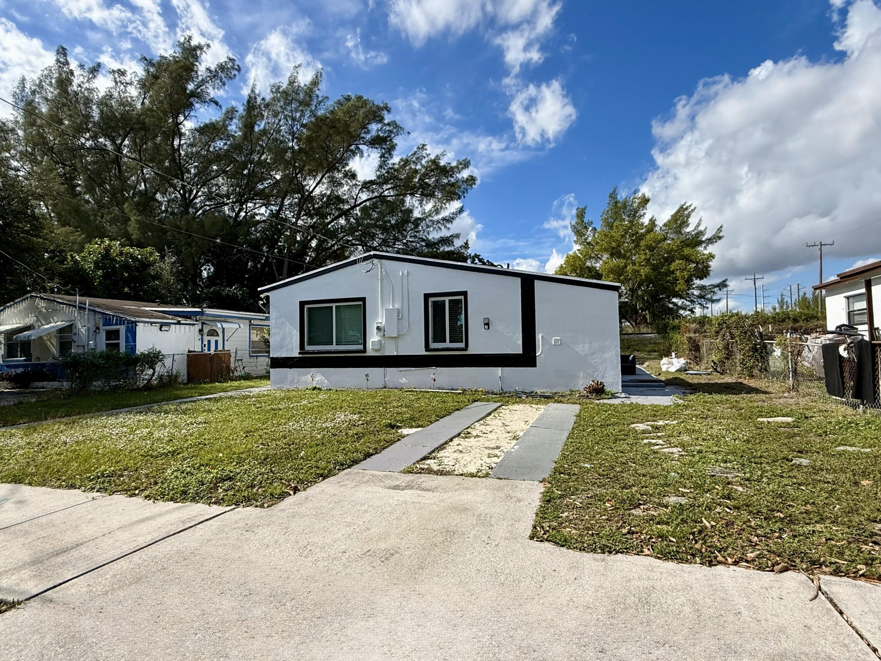 5909 Pinewood Avenue West Palm Beach, FL 33407 - Photo 2 of 11 a front view of a house with a yard and garage