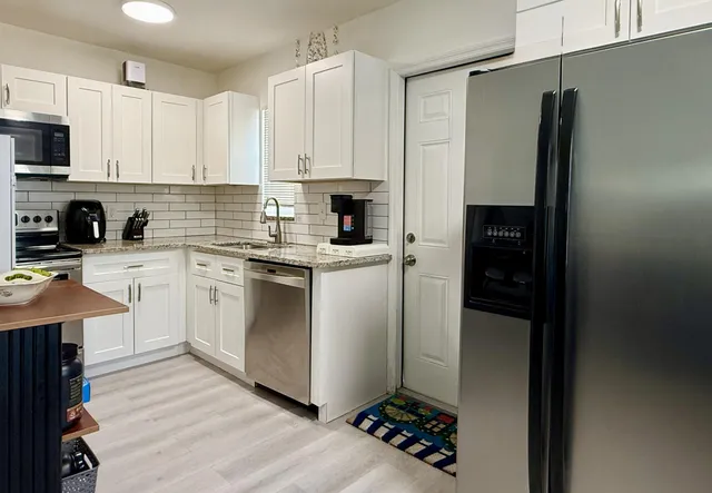 a kitchen with white cabinets and appliances