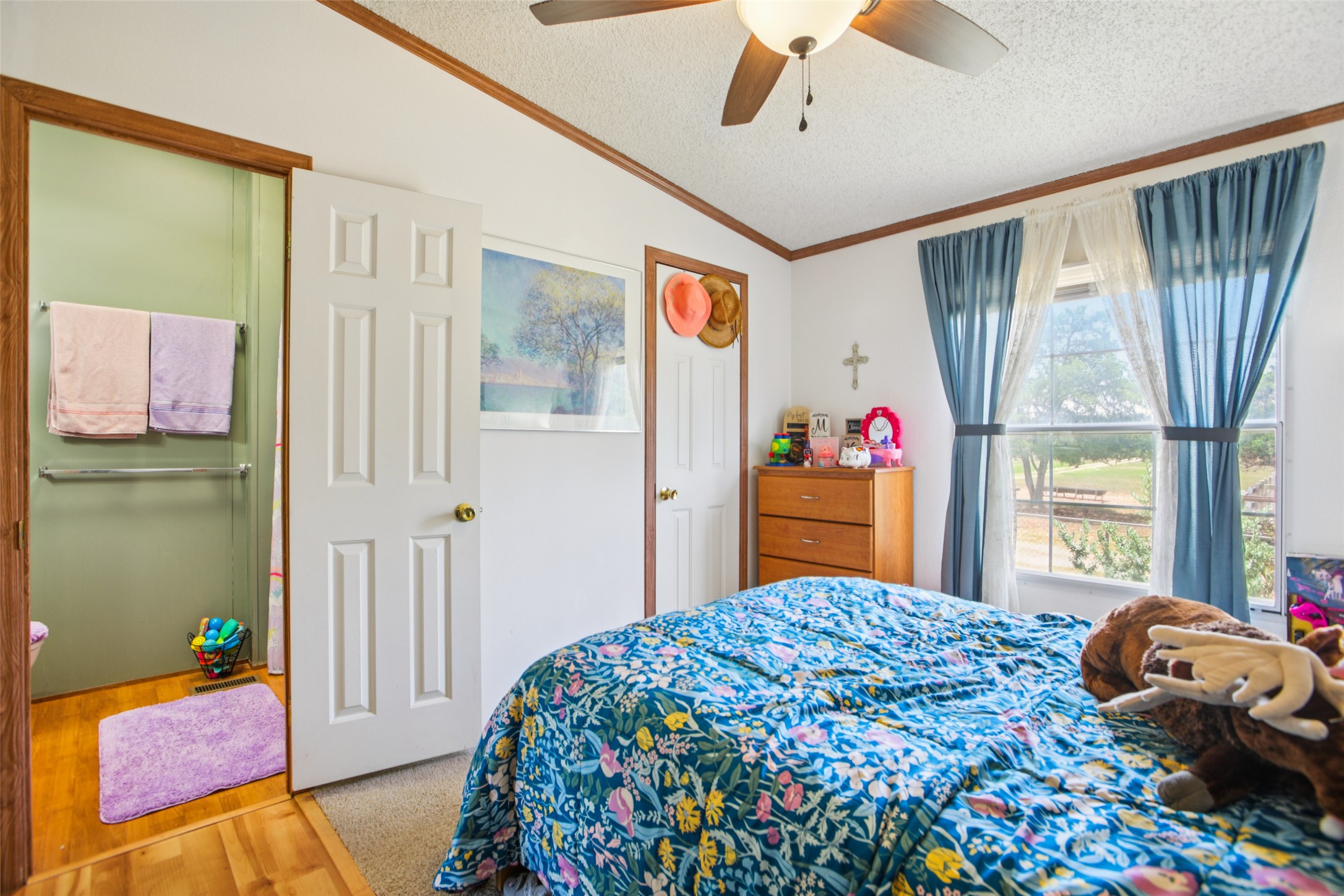 372 Hofferek Road Rosanky, TX 78953 - Photo 25 of 40 Bedroom featuring vaulted ceiling, crown molding, a textured ceiling, wood finished floors, and a ceiling fan