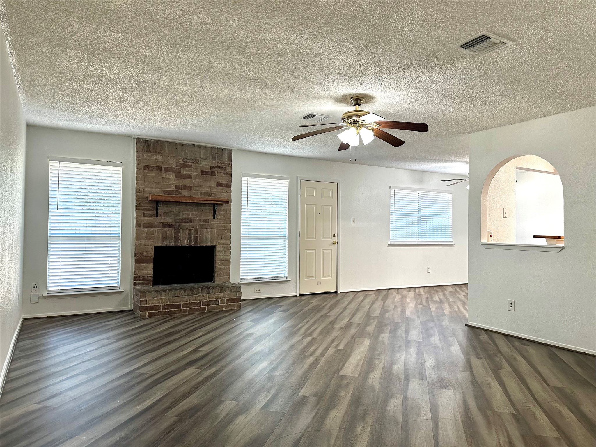 4927 Adonis Drive Spring, TX 77373 - Photo 2 of 11 an empty room with wooden floor a ceiling fan a fireplace and windows