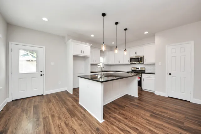 a kitchen with stainless steel appliances granite countertop a sink a stove and a wooden floors