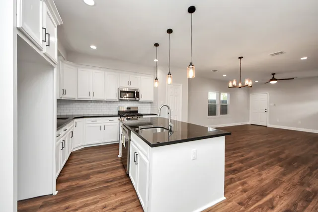 a kitchen with stainless steel appliances kitchen island wooden floors wooden cabinets and a sink