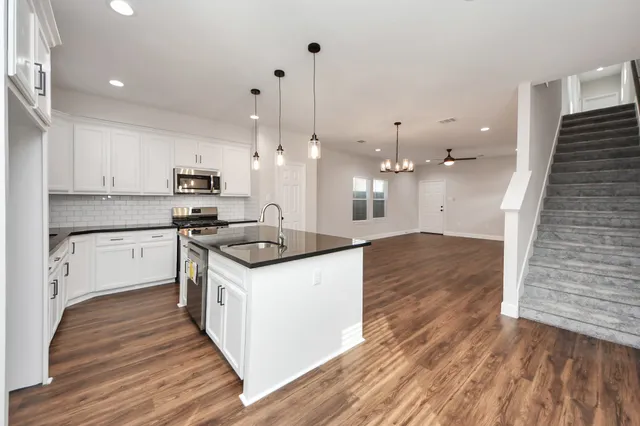 a kitchen with stainless steel appliances granite countertop a sink a stove and a refrigerator