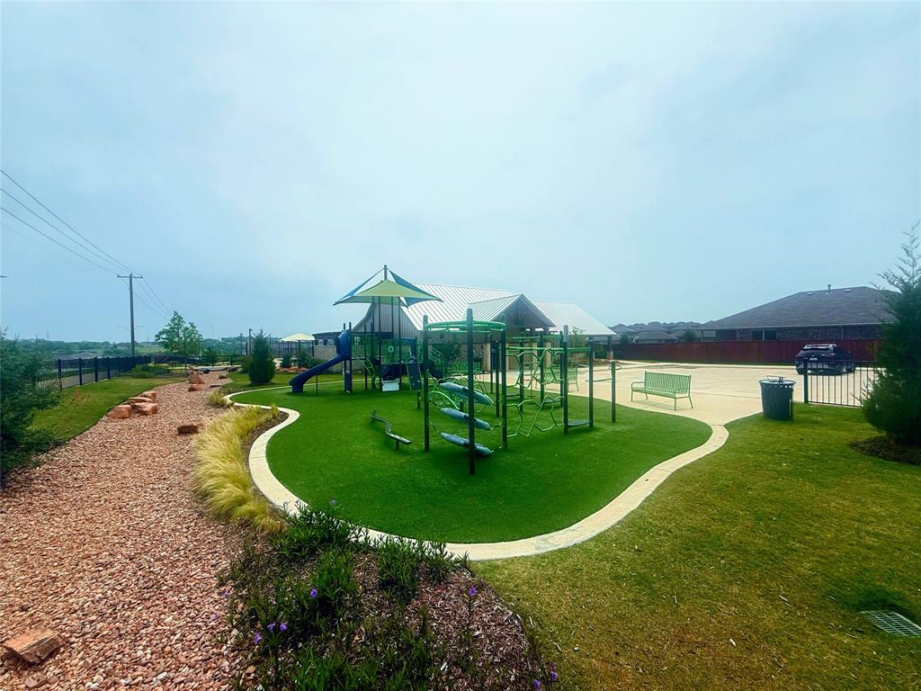 9604 Cherryville Road Fort Worth, TX 76108 - Photo 37 of 40 Outdoor play area featuring a multi-component play structure, artificial turf surfacing, a covered pavilion, and a gravel walking path with natural stone accents