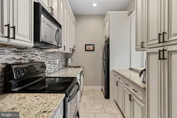 a kitchen with granite countertop a sink stove and refrigerator