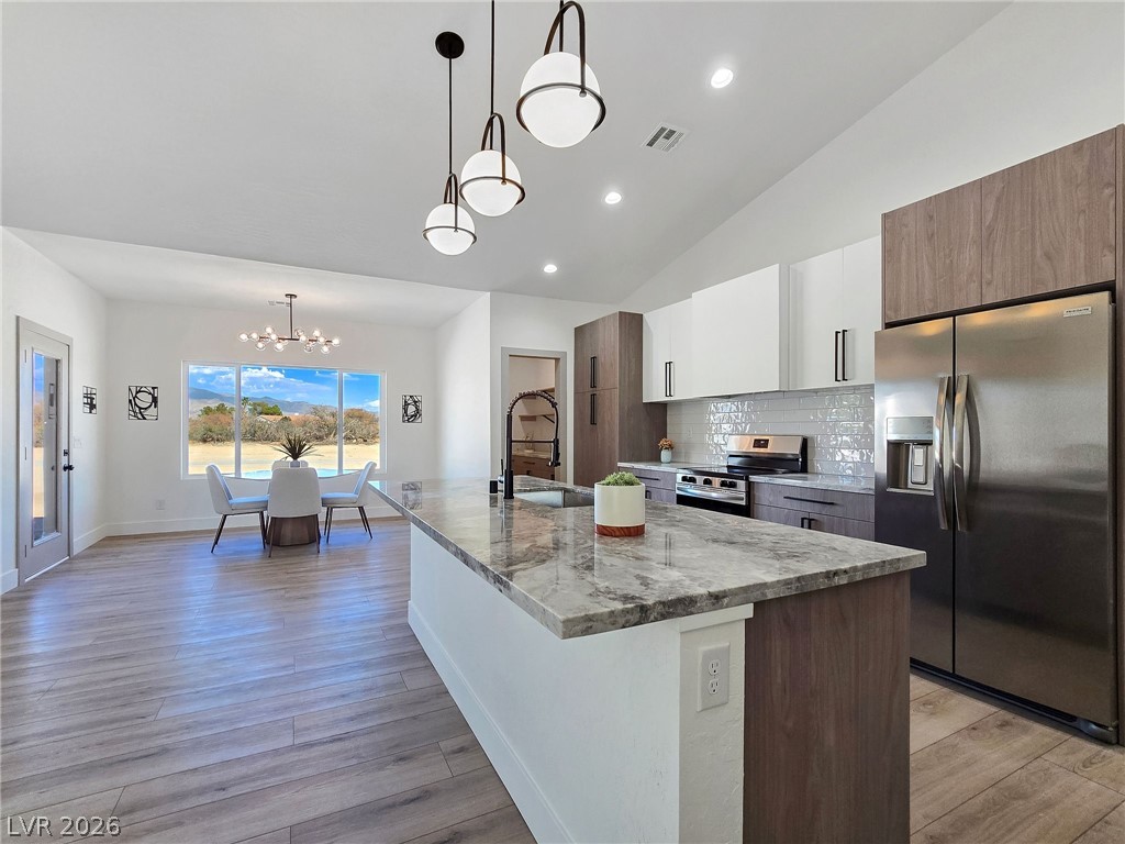 1120 West Gamebird Road Pahrump, NV 89048 - Photo 28 of 36 Kitchen featuring stainless steel appliances, tasteful backsplash, pendant lighting, light stone countertops, and white cabinets