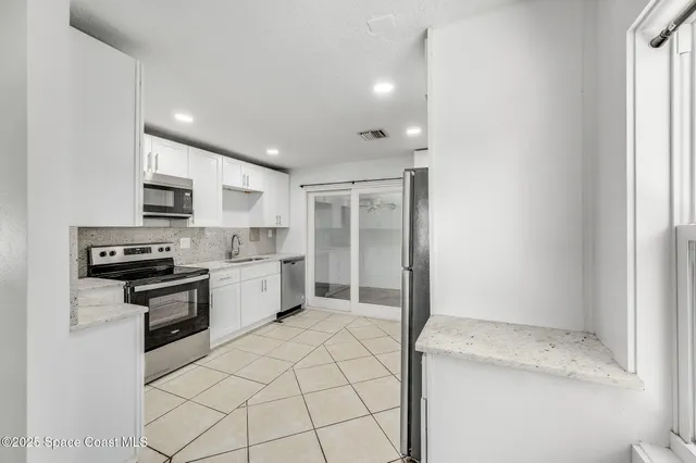 a kitchen with a sink a stove top oven and white stainless steel appliances