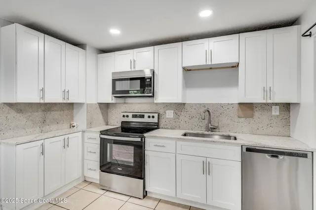 a kitchen with granite countertop white cabinets and white appliances