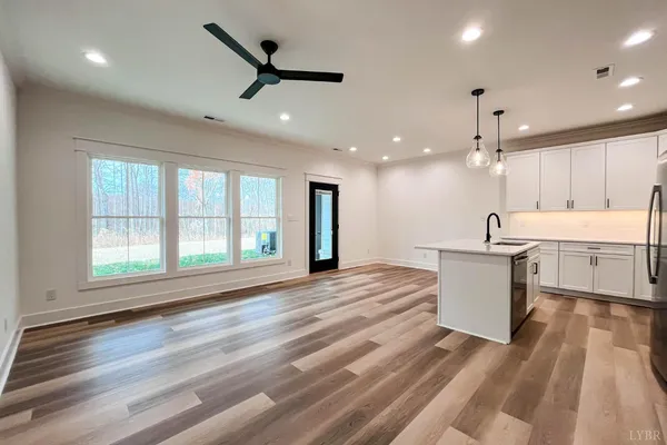 a kitchen with stainless steel appliances granite countertop a refrigerator a sink dishwasher a stove and white cabinets with wooden floor
