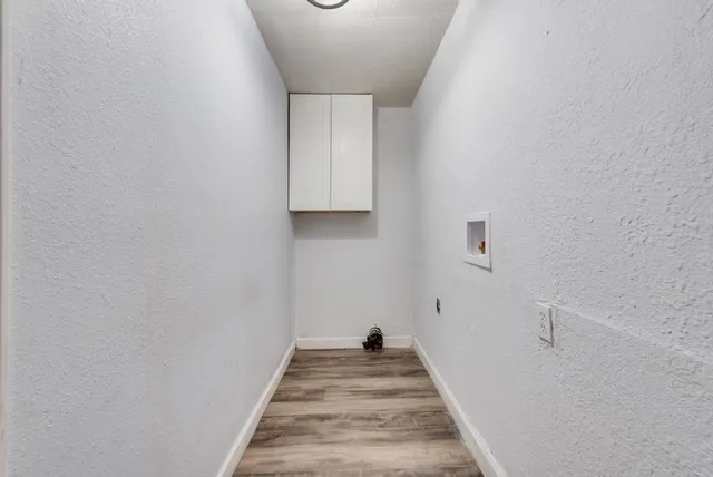 a view of a hallway with wooden floor and a bathroom