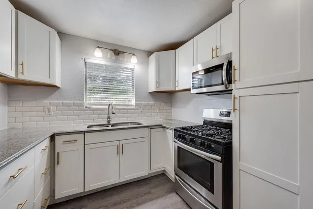 a kitchen with cabinets stainless steel appliances a sink and a window