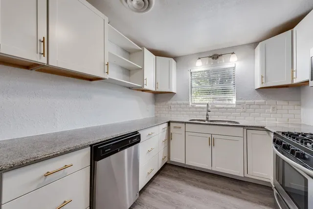 a kitchen with stainless steel appliances granite countertop a sink a stove a microwave and cabinets