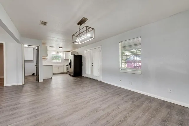 a view of a kitchen with a refrigerator a stove top oven cabinets and wooden floor