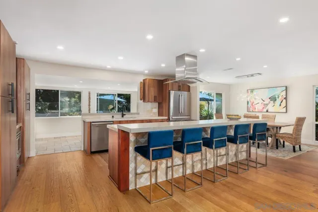 a kitchen with stainless steel appliances granite countertop a kitchen island hardwood floor sink stove dining table and chairs