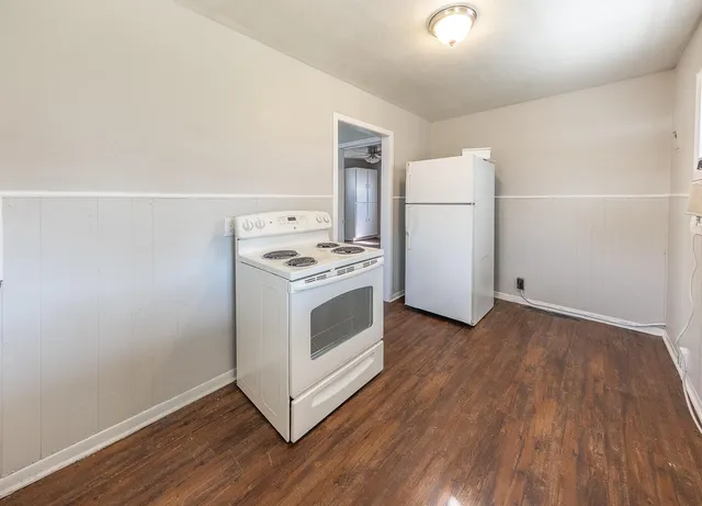 a kitchen with a wooden floor and white stainless steel appliances
