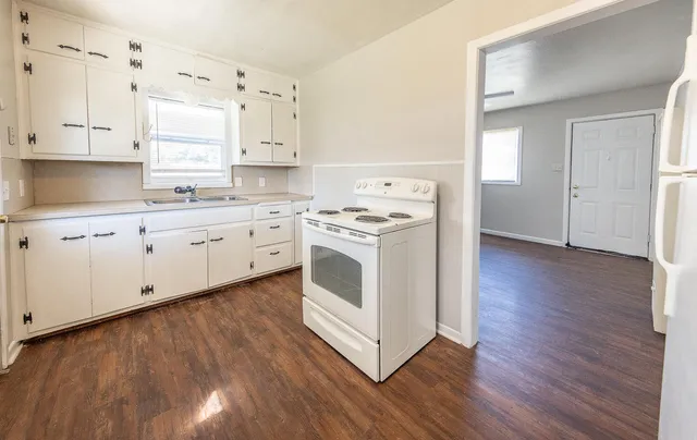 a kitchen with wooden floors and white cabinets