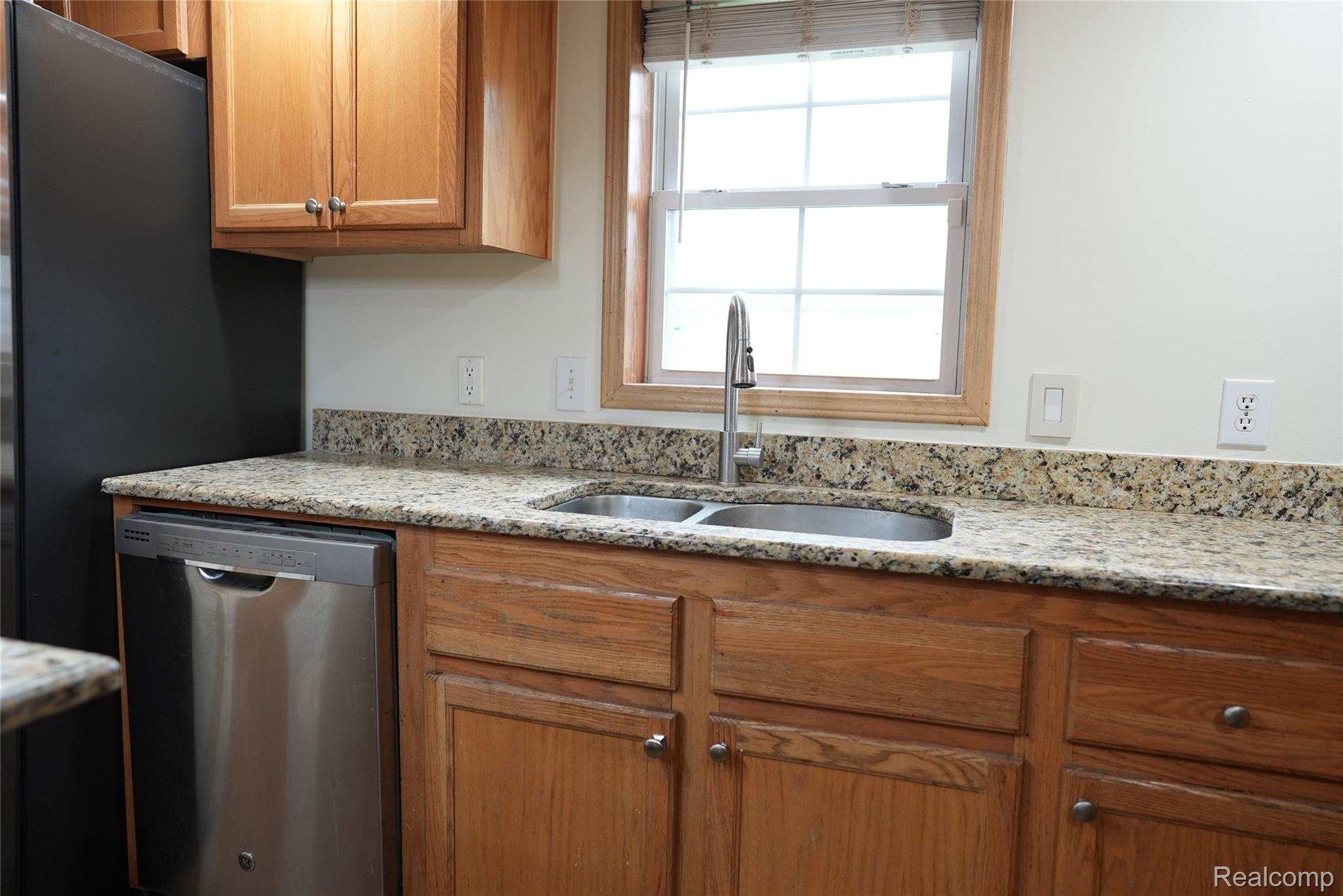 2018 John R Road Troy, MI 48083 - Photo 16 of 57 Natural wood cabinetry with brushed nickel hardware, stainless steel dishwasher, dual basin sink with gooseneck faucet, and speckled stone countertops