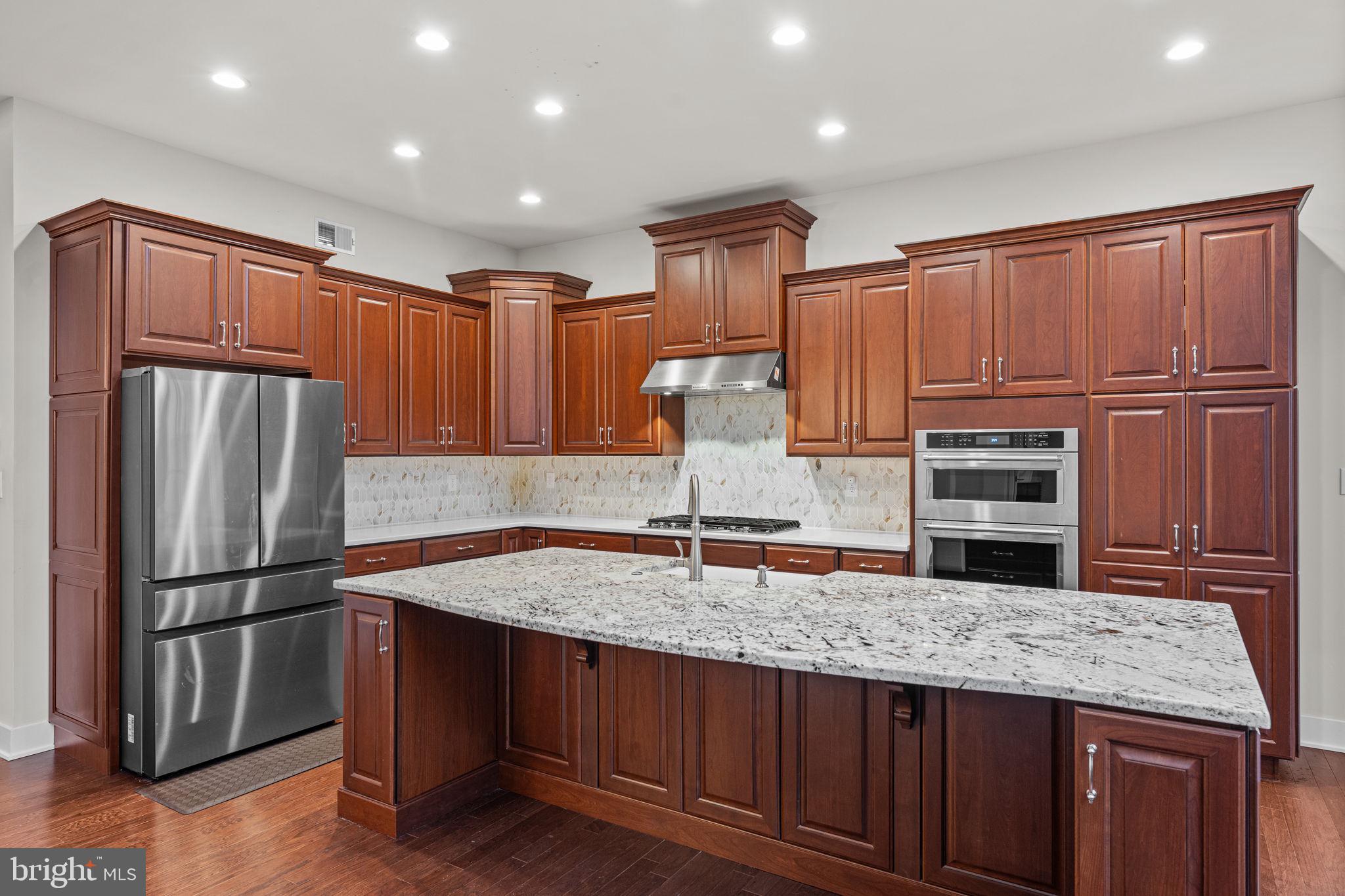 735 Appaloosa Road Downingtown, PA 19335 - Photo 16 of 35 a kitchen with kitchen island granite countertop wooden cabinets a refrigerator and a sink