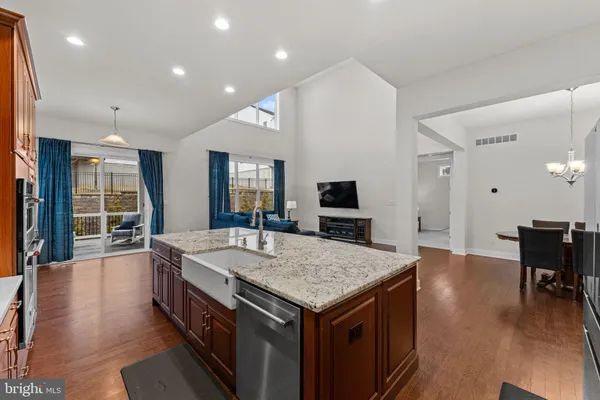 a hall with kitchen island a sink dishwasher a dining table and chairs with wooden floor