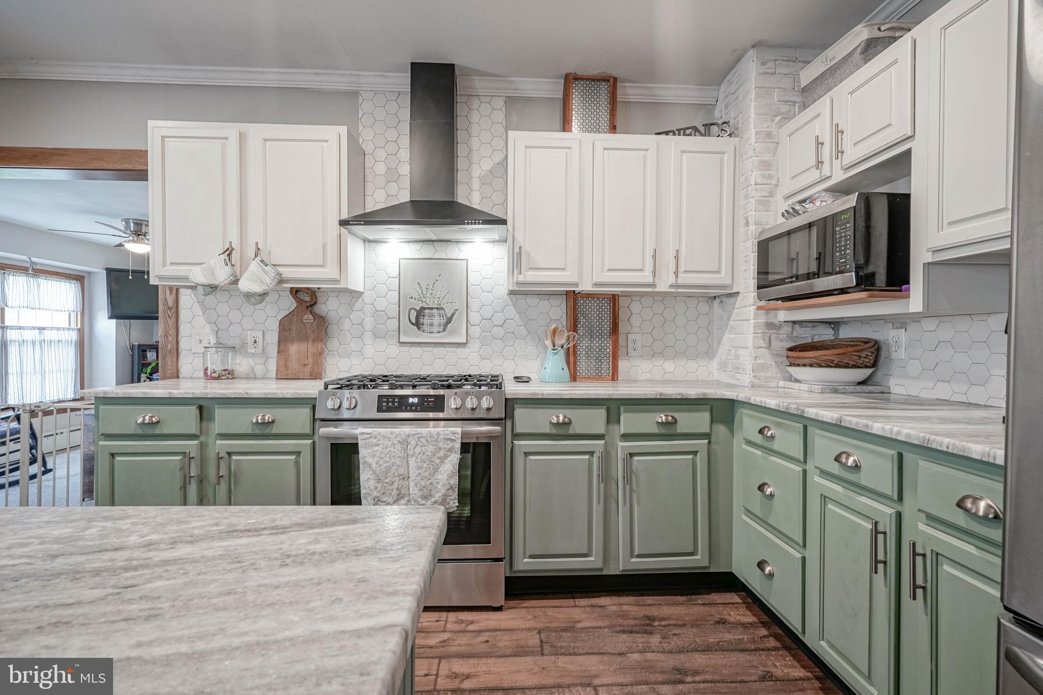 218 Walnut Street Audubon, NJ 08106 - Photo 2 of 40 a kitchen with stainless steel appliances granite countertop a stove top oven a sink dishwasher and white cabinets with wooden floor