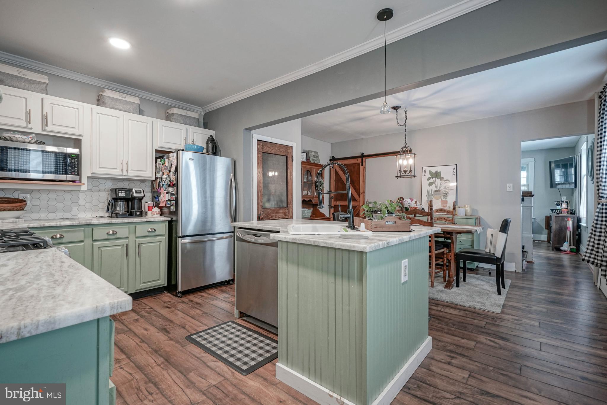 218 Walnut Street Audubon, NJ 08106 - Photo 5 of 40 a kitchen with a refrigerator a microwave oven a sink dishwasher and white cabinets with wooden floor