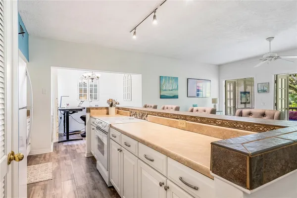 a large white kitchen with stainless steel appliances granite countertop a lot of counter space and wooden floors