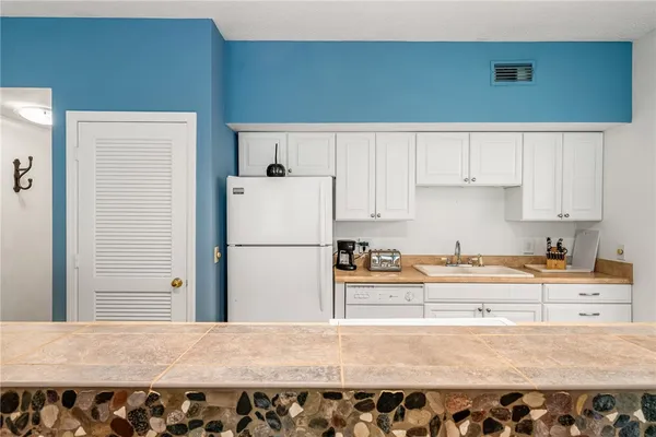 a kitchen with a refrigerator a stove and white cabinets