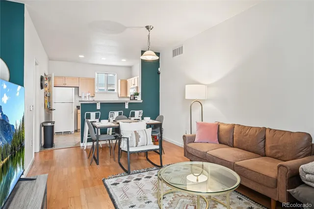 a living room with furniture kitchen view and a wooden floor