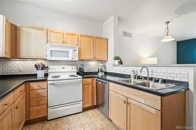 a kitchen with granite countertop white cabinets sink and white appliances