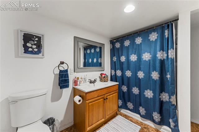 10158 Angeles Road Peyton, CO 80831 - Photo 33 of 43 Bathroom with toilet, a shower with shower curtain, vanity, and baseboards