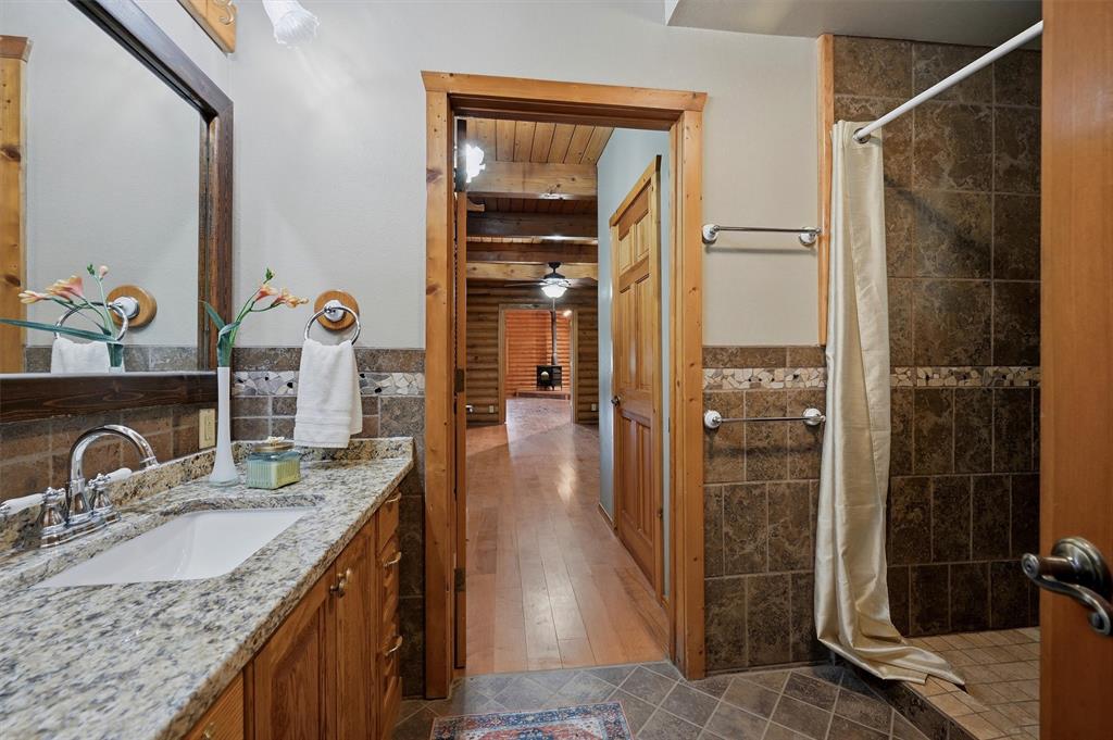 570 Ayres Road Bells, TX 75414 - Photo 23 of 40 a bathroom with a granite countertop sink a mirror and shower