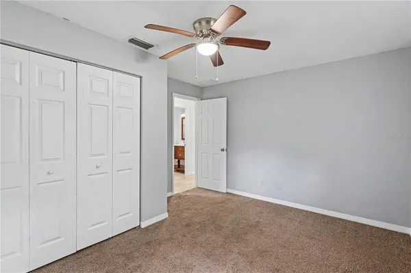 an empty room with windows and fan