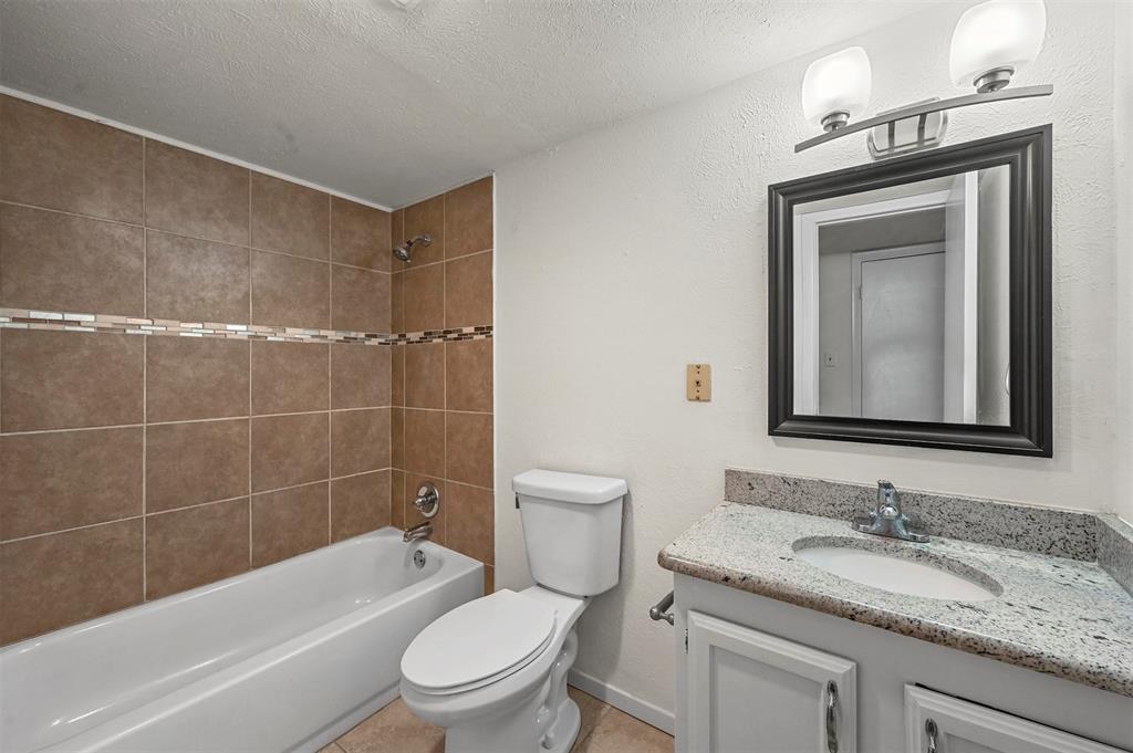 718 Roaming Rd Drive Allen, TX 75002 - Photo 14 of 21 Full bathroom featuring vanity, shower combination, a textured ceiling, and a textured wall