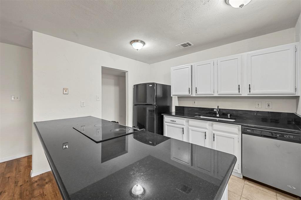 718 Roaming Rd Drive Allen, TX 75002 - Photo 5 of 21 Kitchen featuring black appliances, white cabinetry, dark stone counters, a peninsula, and a textured ceiling