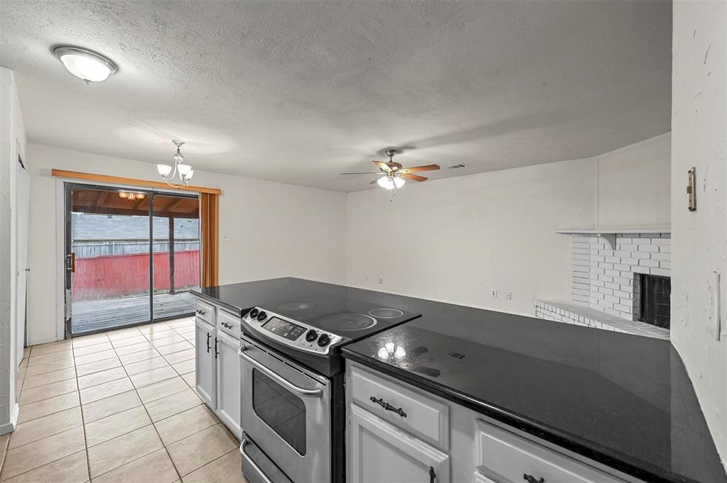 718 Roaming Rd Drive Allen, TX 75002 - Photo 7 of 21 Kitchen with electric range, a ceiling fan, white cabinets, a fireplace, and a textured ceiling