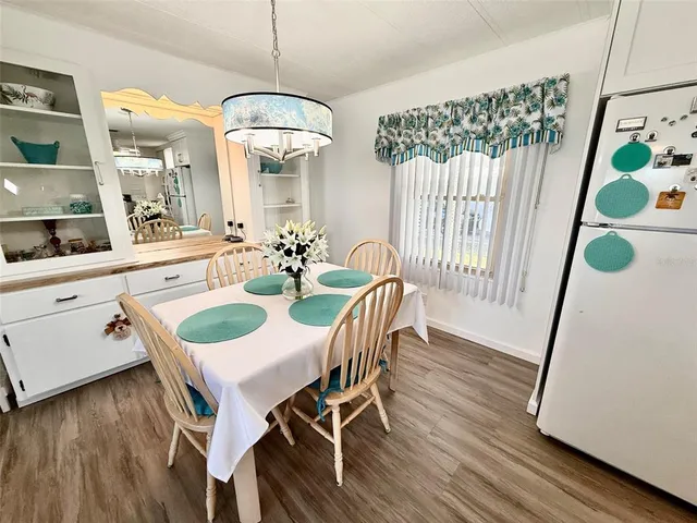 a kitchen with stainless steel appliances granite countertop a refrigerator a stove a sink and white cabinets with wooden floor