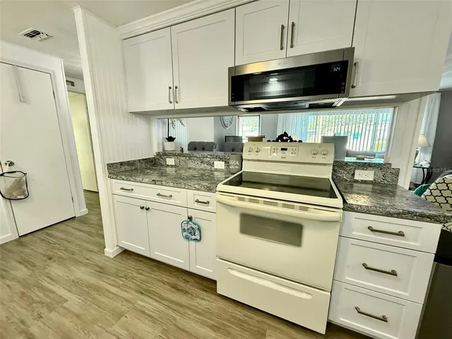 a kitchen with a stove and a wooden floor