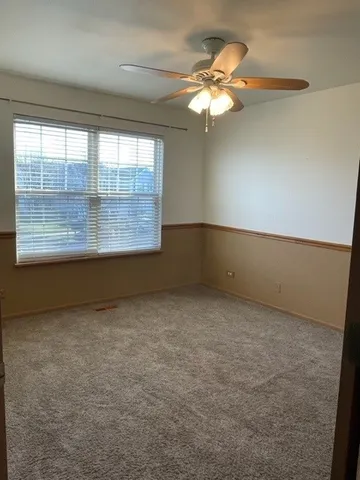 an empty room with a chandelier fan and window