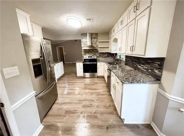 a kitchen with granite countertop a refrigerator a sink a stove a microwave and island