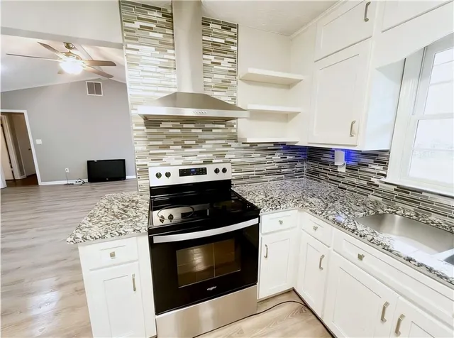 a kitchen with stainless steel appliances granite countertop a stove a sink and a microwave