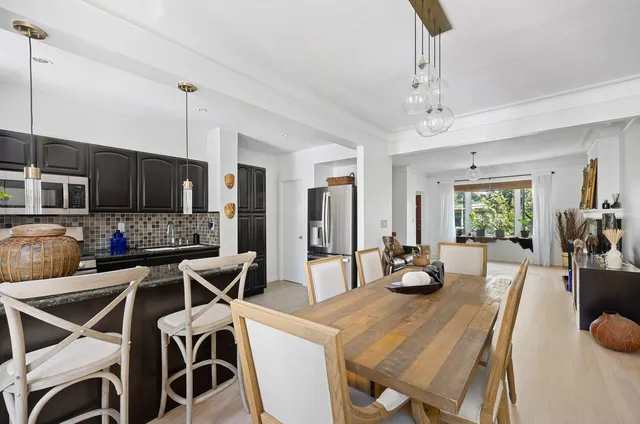 a view of a dining room and livingroom with furniture wooden floor a rug a fireplace and a chandelier