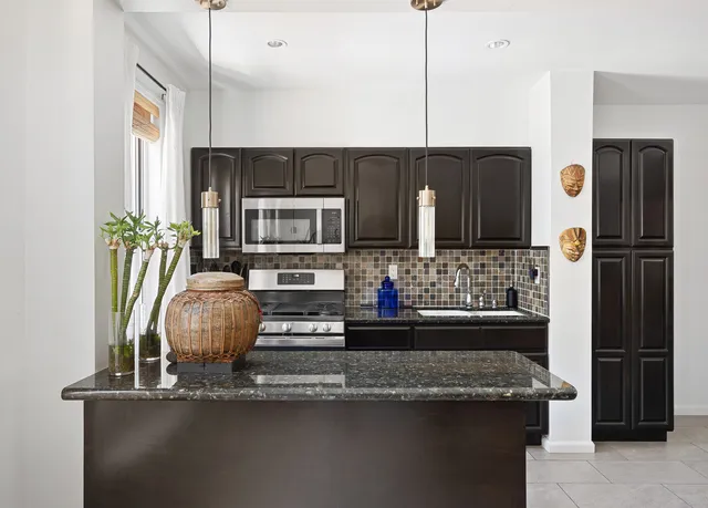 a kitchen with kitchen island granite countertop a refrigerator a stove and a microwave