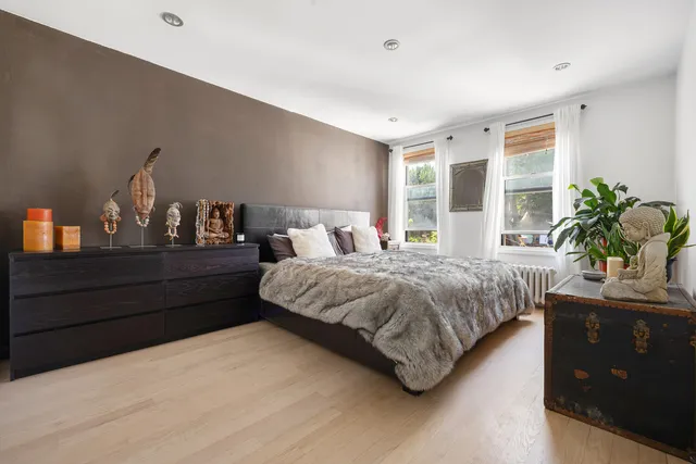 a bedroom with a large bed and a potted plant on dresser