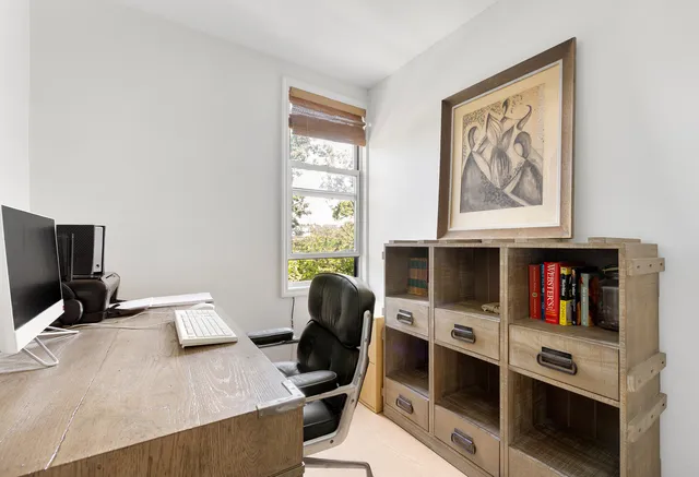 a view of a workspace with furniture and a window