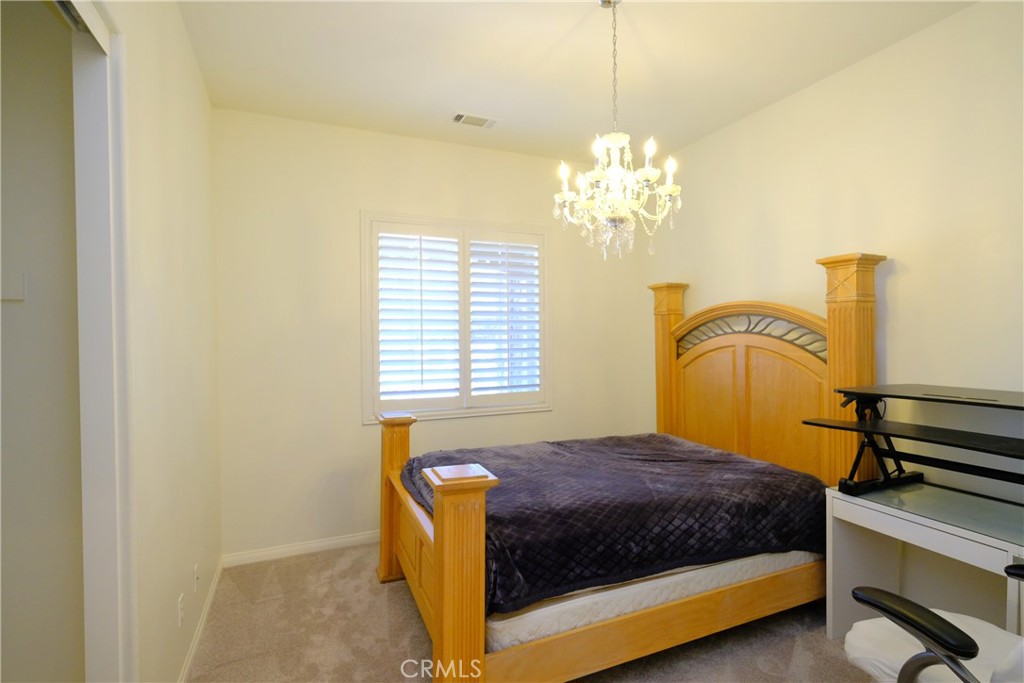 1791 Hannon Road Cherry Valley, CA 92223 - Photo 26 of 41 a bedroom with a bed and a chandelier