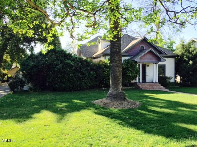 a front view of a house with a yard and large tree