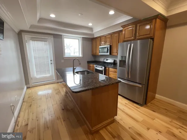 a kitchen with stainless steel appliances granite countertop a refrigerator a stove a sink and dishwasher with wooden floor