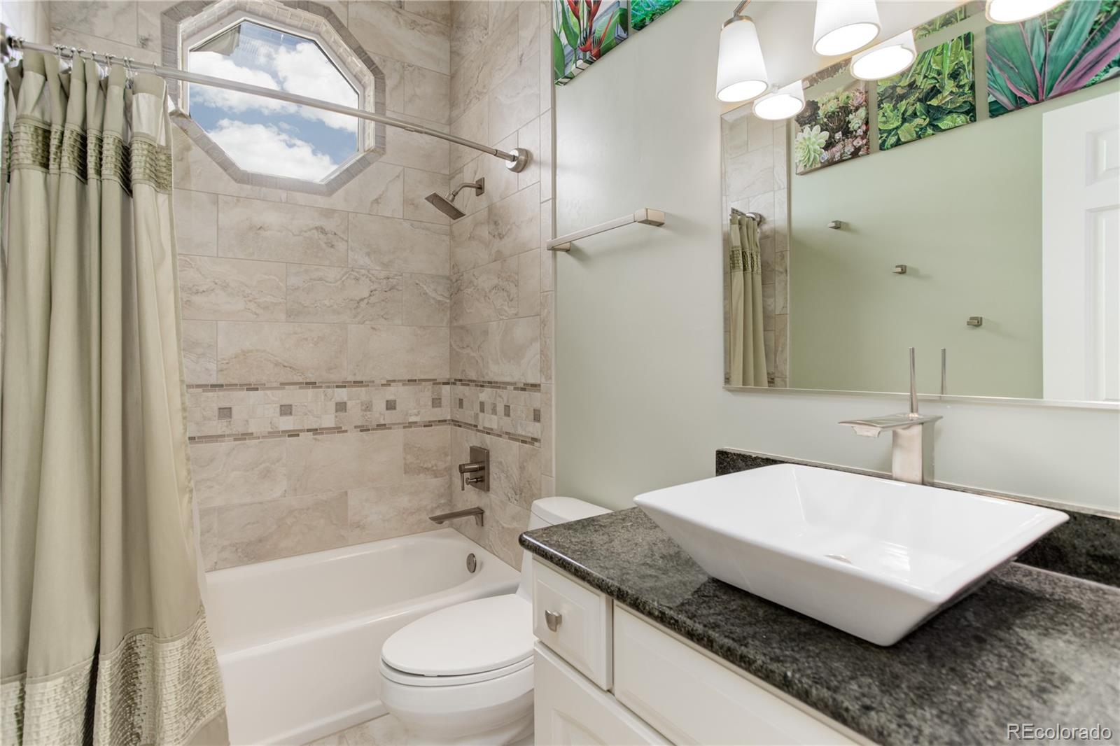 24943 Ben Kelly Road Elbert, CO 80106 - Photo 13 of 39 a bathroom with a granite countertop sink a toilet a mirror and bathtub